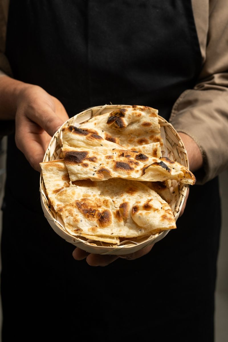 A server presenting a basket of freshly baked naan